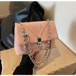 Detail of pink quilted crossbody bag with silver chain strap and metal ball accessory