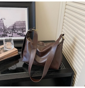Détail du sac à bandoulière marron foncé en similicuir avec boucle dorée et texture