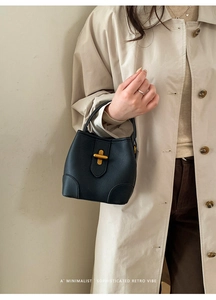 Detail of a black leather bucket bag featuring a sophisticated gold metal twist lock closure