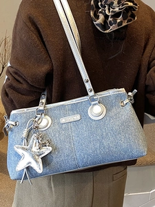 Blaue Denim Schultertasche mit silbernem Sternanhänger und Nieten am Modell