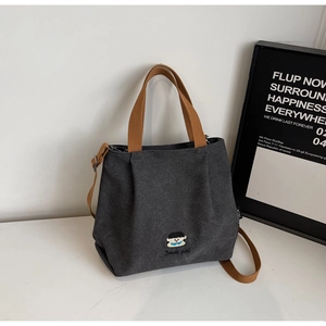 Detailed view of embroidery and contrast brown straps on dark grey canvas tote bag