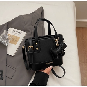 Detail of black canvas bucket bag with leather trim and cute puppy charm accessory