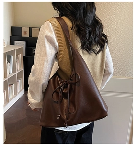 Detail of a dark brown PU leather tote bag with ribbon bow and soft grain texture