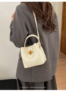 White lychee leather bucket bag with gold T-lock shown on a model in gray blazer