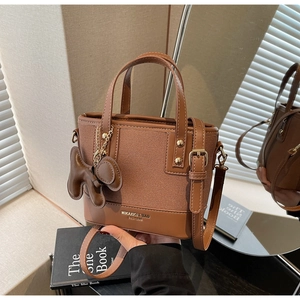 Detail of a brown leather tote bag with elephant charm on stylish fashion books