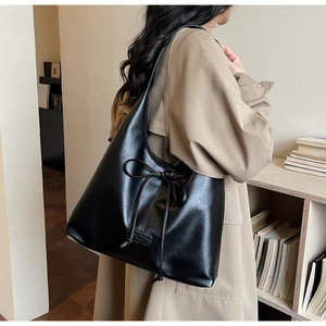 Detail of black large capacity tote bag with bow decoration shown on a model