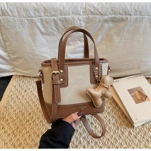Detail of canvas tote bag with brown leather trim and a cute gingerbread man charm