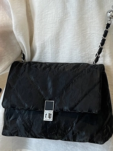 Fashionable black quilted chain shoulder bag with metallic crinkled texture and silver clasp