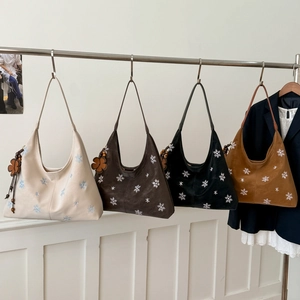 Detail view of four textured tote bags with snowflake embroidery and clover leaf pendants