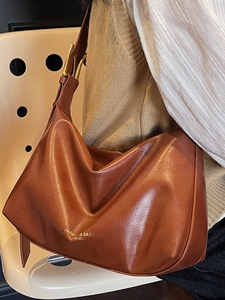 Sac cabas en cuir marron avec bandoulière réglable et texte de mode porté par un mannequin