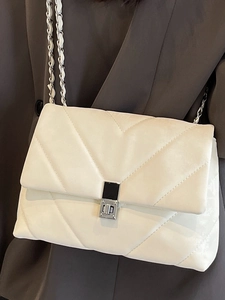 White quilted shoulder bag with V-shaped stitching and silver chain strap on a model