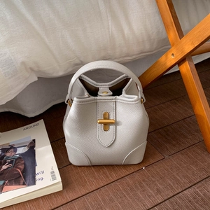 Detailed view of white lychee leather bucket bag with golden twist lock and top handle