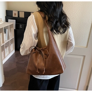 Detailed macro view of large brown faux leather tote bag with stylish bow drawstring detail