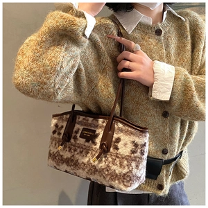 Detail of plush tote bag with zebra pattern and brown leather straps on shoulder