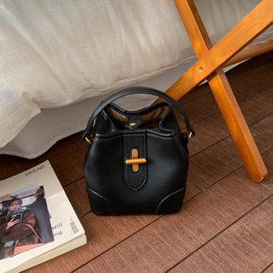Detail of black lychee grain leather bucket bag with a gold metal twist lock