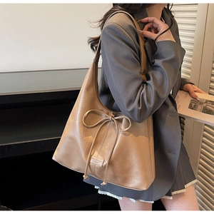 Detailed close-up of large khaki tote bag with drawstring bow and smooth leather texture