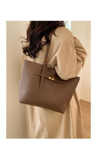 Detail of lychee pattern leather tote bag with gold metal buckle and slender shoulder strap