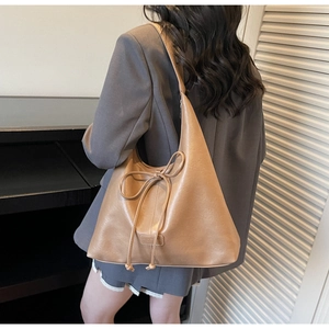 Detail of camel brown tote bag with decorative bow and premium faux leather texture