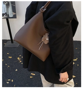 Détail du sac hobo en cuir grainé marron foncé avec charm en peluche et logo latéral