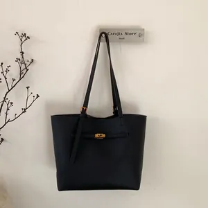 Detail of black tote bag featuring pebbled leather texture and gold-tone twist lock buckle