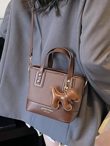 Chic dark brown mixed material bucket bag with a cute dog charm for casual commuting style