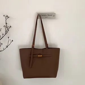 Close-up of coffee brown tote bag with litchi grain texture and gold metal accents
