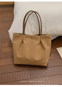 Detail of minimalist khaki canvas tote bag with magnetic closure and brown straps