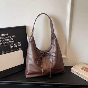 Detail of soft brown hobo bag featuring decorative bow and elegant leather grain texture