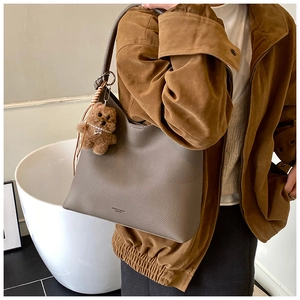 Détail du sac bandoulière taupe en cuir grainé avec un charmant ours en peluche brun