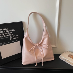 Close-up of pink pebbled faux leather tote bag with stylish bow tie and brand logo