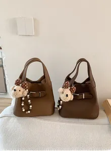 Detail of leather bucket bags with teddy bear charms and adjustable strap closures