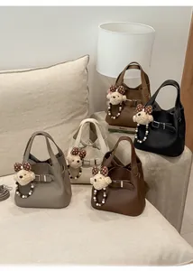 Close-up of pebble leather bucket bags in five colors with cute teddy bear charms
