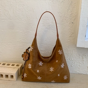 Close-up of brown hobo bag with snowflake embroidery and floral wood bead charm