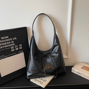 Detail of black matte PU leather hobo bag with ribbon bow and minimalist branding