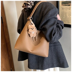 Sac cabas marron avec breloque ours porté par un mannequin en veste de blazer