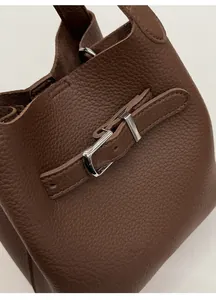 Macro shot of dark brown pebbled leather texture and silver buckle detail on bucket bag
