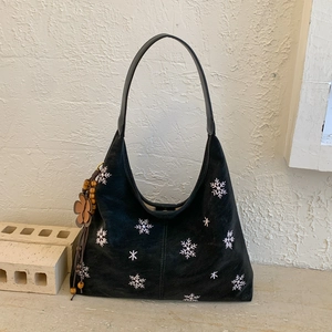 Detail of black hobo bag with snowflake embroidery and floral beaded pendant decoration