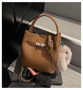 Détail du sac seau en cuir grainé marron avec fermoir argenté et breloque lapin en peluche