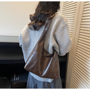 Detail of dark brown faux suede tote bag with large outer pocket and wide shoulder strap