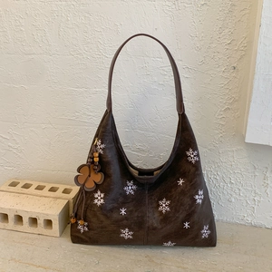 Detail of dark brown faux suede hobo bag with snowflake embroidery and tassel charm