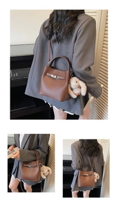 Détail d'un sac à main en cuir marron avec fermoir métallique et breloque lapin en peluche