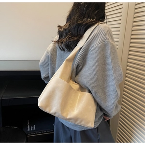 Detailed close-up of cream faux suede hobo tote with front pockets and visible stitching
