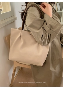 Detail view of beige large tote bag with soft pleated design and brown shoulder strap