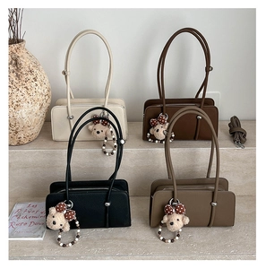 Chic baguette bags in four colors with bear pendants on stone steps display