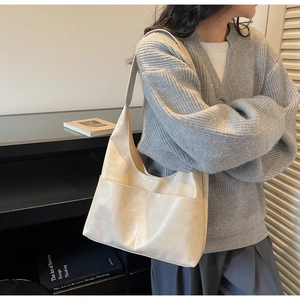 Detail of minimalist beige suede tote bag styled on shoulder with modern interior background