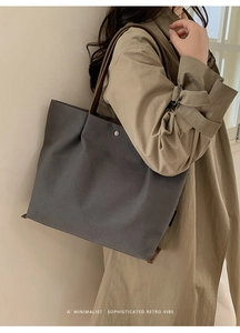 Detail of the high-quality grey canvas tote bag with brown leather straps on a model