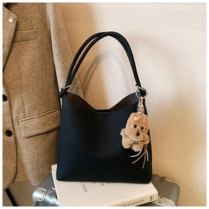Détail du sac cabas en cuir noir avec un pendentif en peluche en forme de chien
