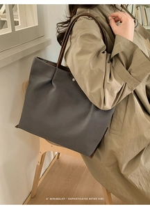 Minimalist dark gray tote bag with leather straps worn by a model for a retro vibe