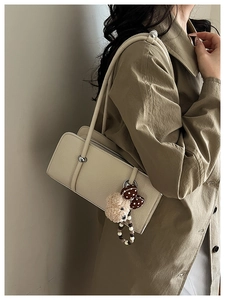Detail of cream shoulder bag featuring a cute plush bear pendant and polka dot bow