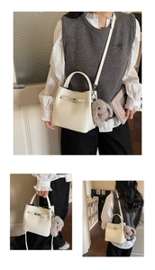 Vue détaillée du sac seau beige texture lychee avec fermoir rotatif en métal et breloque lapin